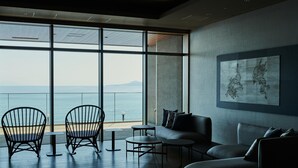 A modern interior with a large window overlooking the sea, a sofa, two chairs, and a small table. - Atami Izusan KARAKU（ORIX HOTELS & RESORTS） (Atami)