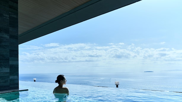A person in an infinity pool with a view of the sea and clouds. - Atami Izusan KARAKU（ORIX HOTELS & RESORTS） (Atami)