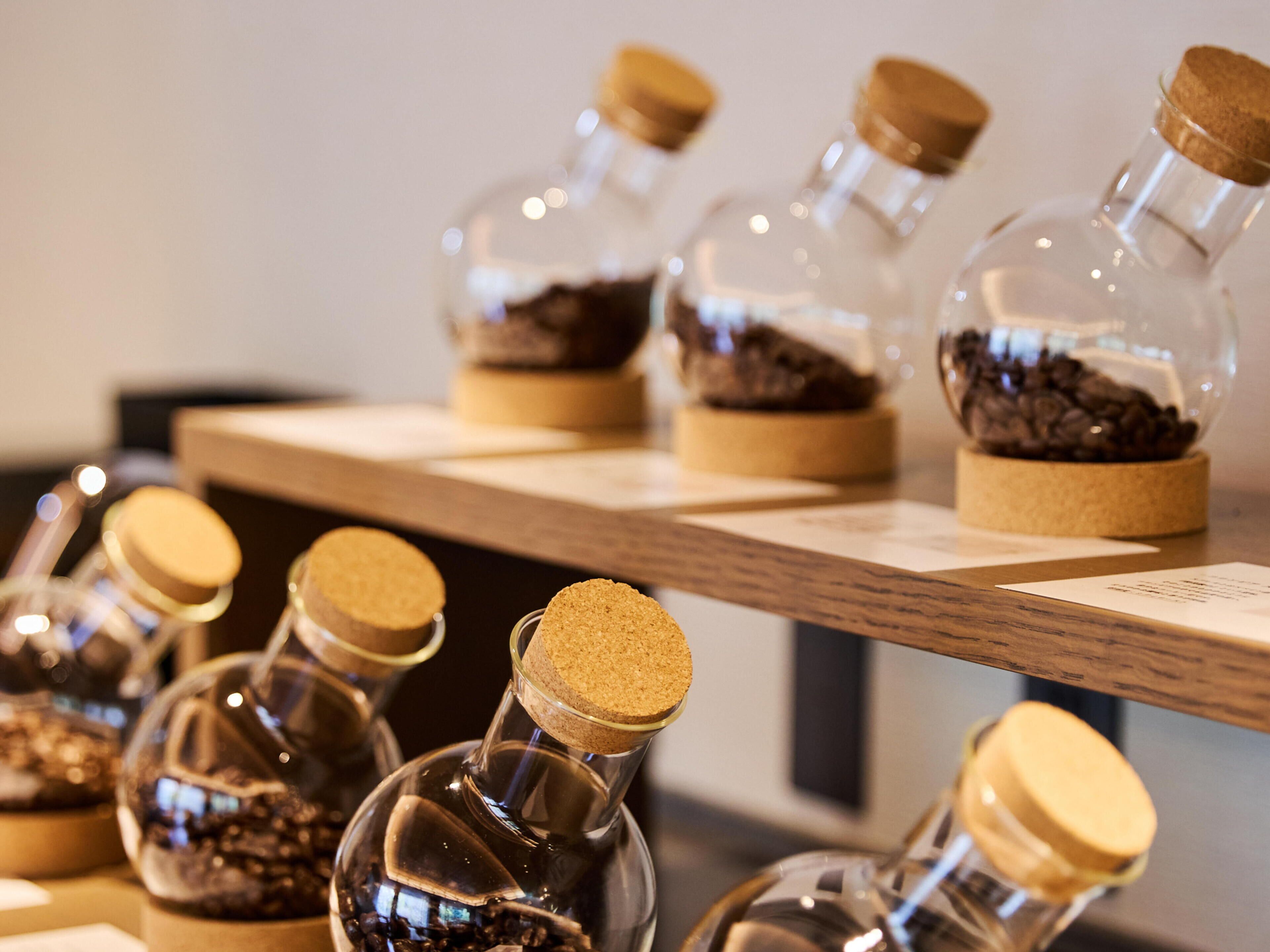 A display of glass bottles with cork stoppers containing coffee beans.