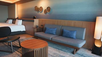 A hotel room with a bed, a sofa, a coffee table, and a lamp.