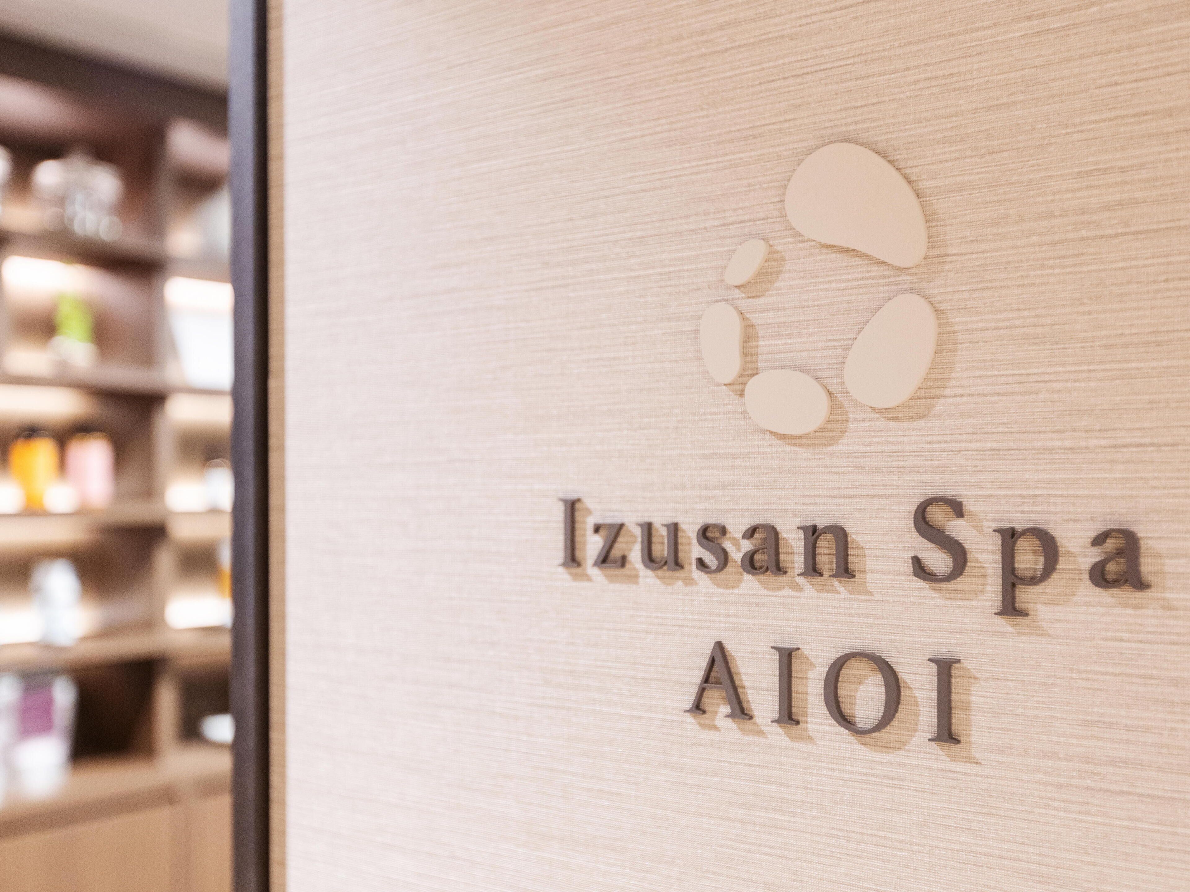 A wooden sign with the text "Izusan Spa AIOI" and a logo above it.