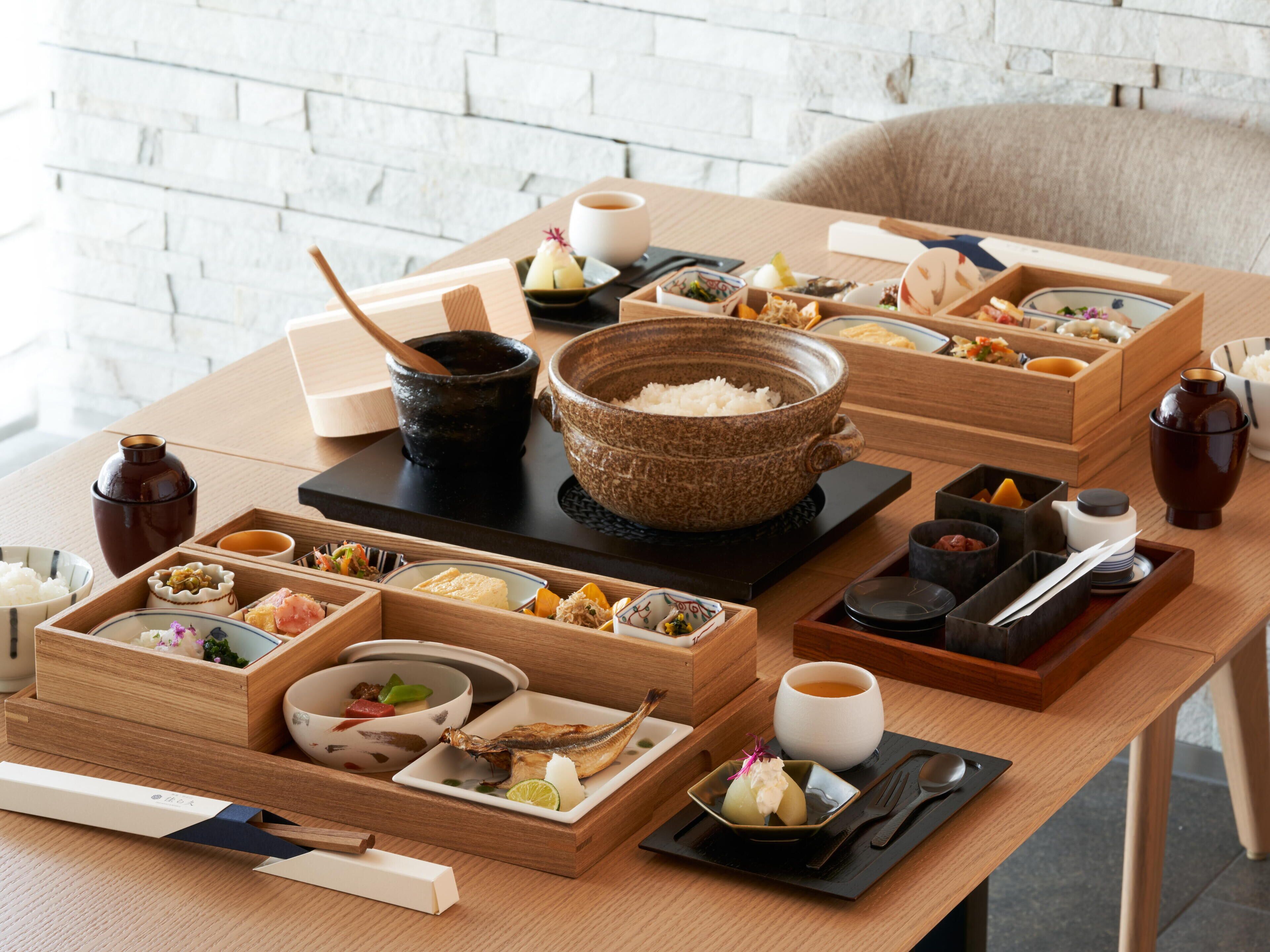 A traditional Japanese meal setup with various dishes and utensils on a wooden table.