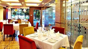 A restaurant with tables set for dining, featuring a view through a glass partition. - West Park Inn (Dhaka)