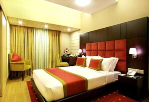 A hotel room with a large bed, a nightstand, a chair, and a curtain. - West Park Inn (Dhaka)