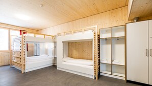 A room with bunk beds, a wardrobe, and a shelf with towels. - Nordic Hostel (Lantsch-Lenz)