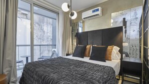 Habitación de hotel moderna con una cama grande, vistas a la ciudad y un balcón.