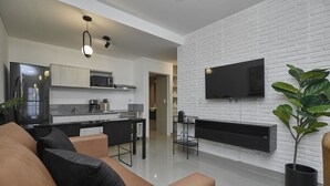 Una sala de estar moderna con un sofá, una mesa de centro y un televisor montado en una pared de ladrillo blanco.