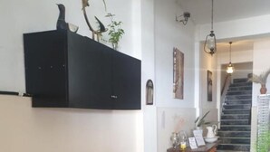 A spacious room with a wooden bench, a small table with a pitcher, and a black cabinet with decorative items. - Riviera Seaside Hotel by Estia (Corfu)