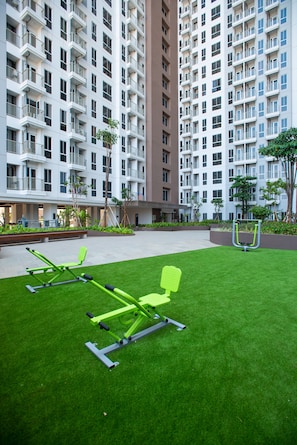 A modern apartment building with multiple balconies and a well-maintained courtyard with exercise equipment.