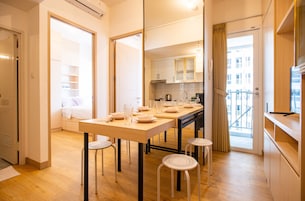 Une cuisine moderne avec un coin repas, un plancher en bois et une vue sur la ville par la fenêtre.