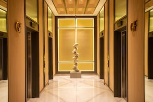 Un couloir doté d’ascenseurs, d’un sol en marbre et d’une sculpture décorative.