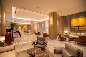 Un hall d’entrée spacieux, doté d’un mobilier moderne, d’un grand espace salon et d’une œuvre d’art remarquable accrochée au mur.
