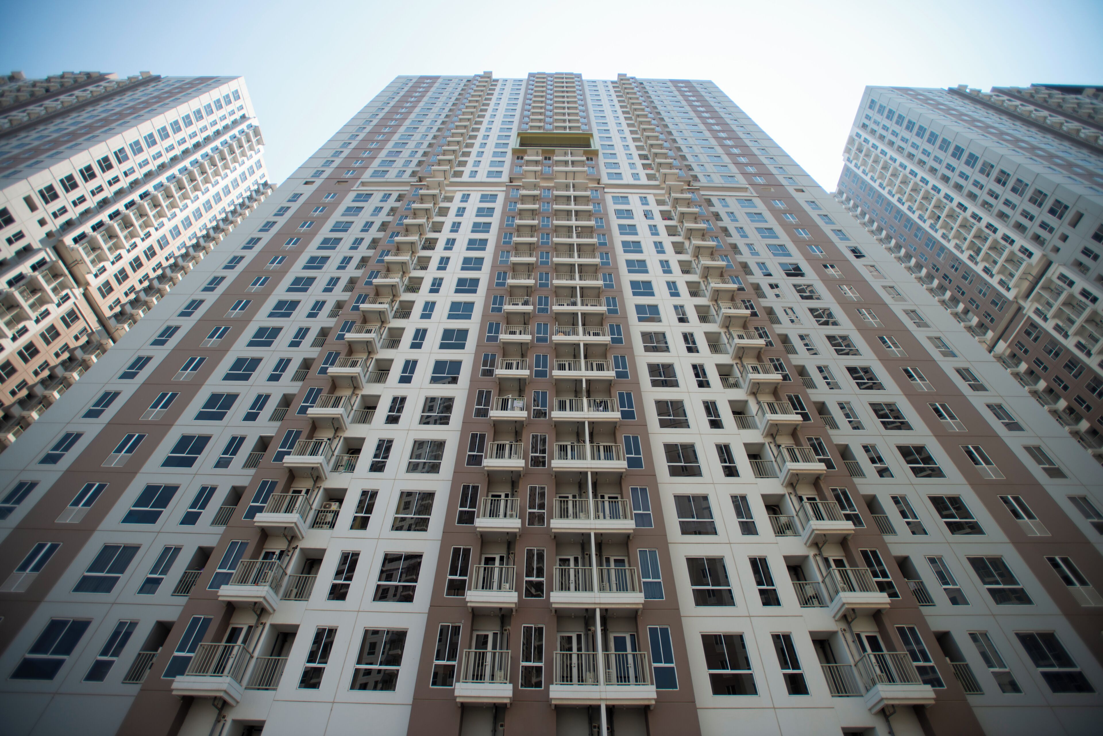 Um edifício residencial alto com várias varandas e fachada uniforme.
