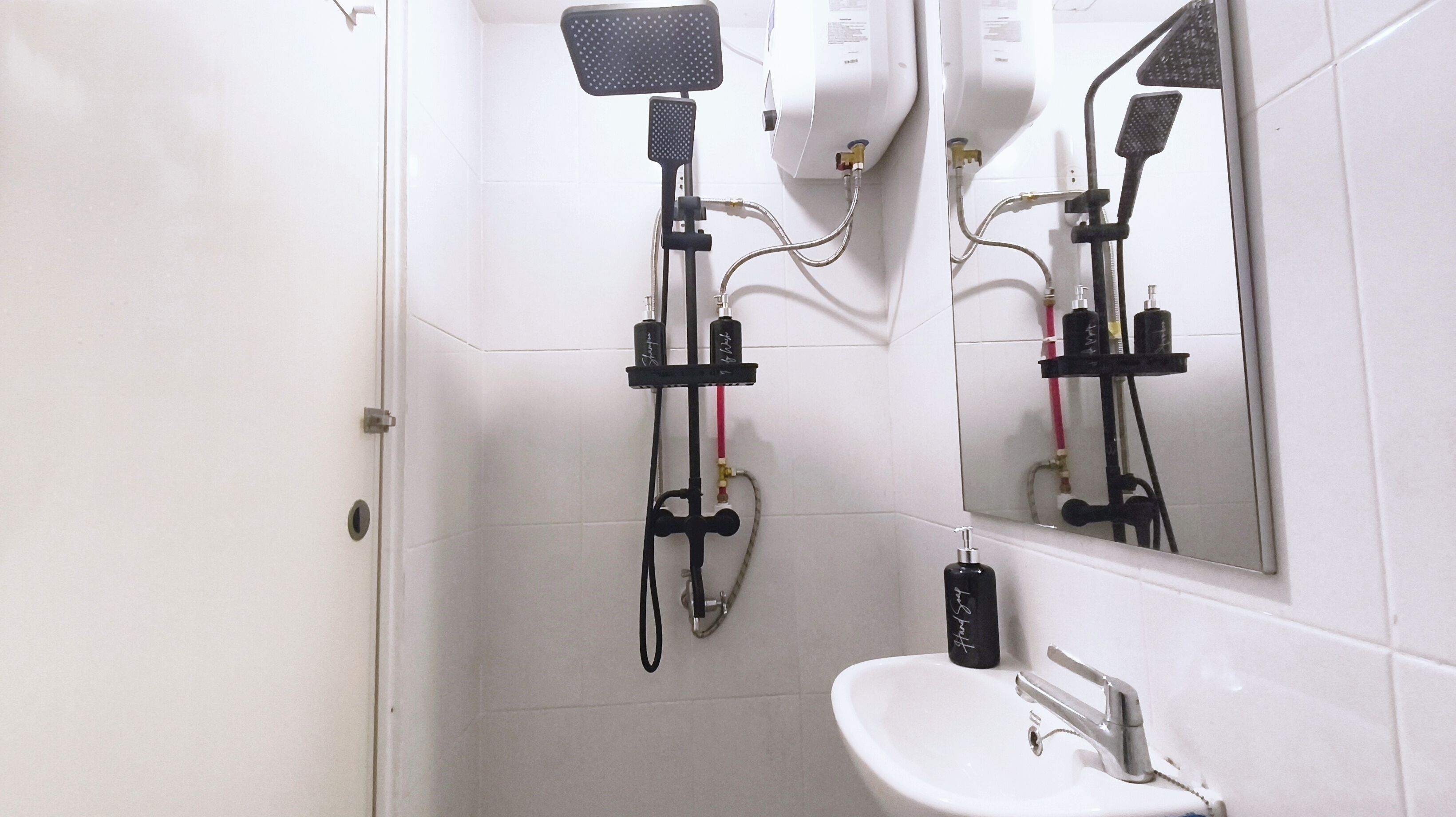 Ein Badezimmer mit einem weißen Waschbecken, einem Spiegel und einer Dusche inklusive Duschbrause.
