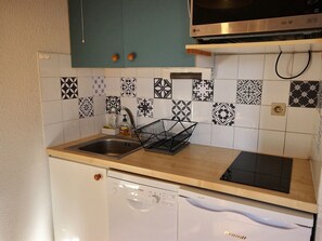 Kitchen features a stainless steel sink, Bosch dishwasher, and microwave oven, along with a black and white patterned backsplash and a green cabinet.