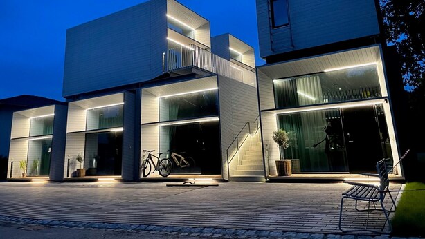 Un edificio moderno con fachada de vidrio, una escalera y una bicicleta estacionada afuera.