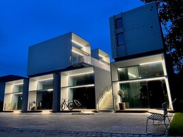 Un edificio moderno con fachada de vidrio, una escalera y una bicicleta estacionada afuera.