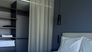 Una habitación de hotel moderna con una cama grande, un armario empotrado y una lámpara colgante.