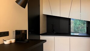 Una cocina moderna con encimera oscura, armarios blancos y una lámpara colgante negra.