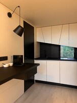 Una cocina moderna con encimera oscura, armarios blancos y una lámpara colgante negra.