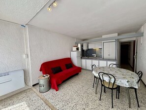 A compact kitchen with a dining area, a red sofa, and a table with chairs.
