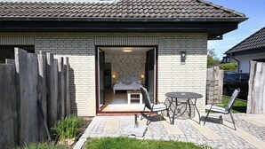 Ein Haus mit einer Terrassenfläche, komplett mit Tisch und Stühlen, einem Holzzaun und einer Ziegelaußenwand.