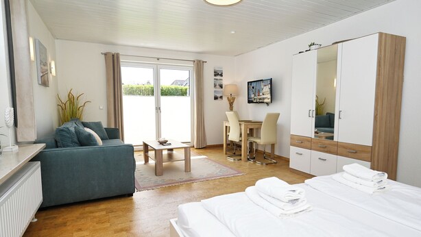 Ein modernes Hotelzimmer mit Bett, Sofa, Schreibtisch und Kleiderschrank.