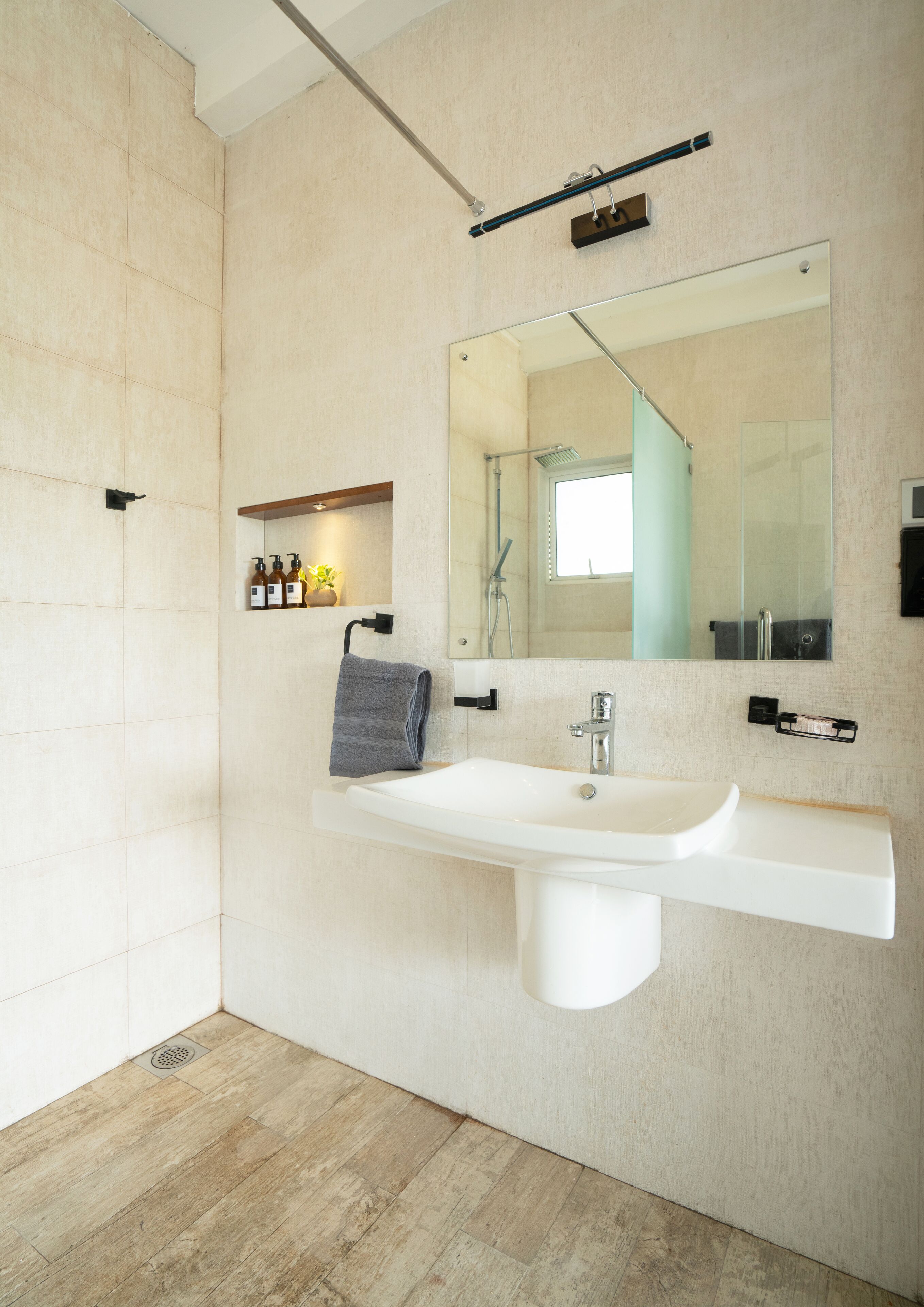 Une salle de bain moderne avec un grand miroir, un lavabo blanc et un espace douche.