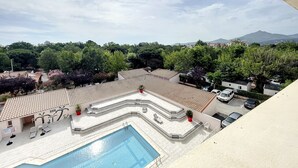 A rooftop pool area with a swimming pool, sun loungers, and a view of surrounding trees and mountains. - Duplex T4 avec piscine, 6 couchages, garage, proche plage à Argelès-sur-Mer (Argelès-sur-Mer)