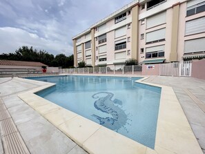 En swimmingpool med en kant som är klädd med kakel och en stege.