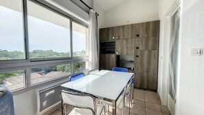 A modern kitchen with a large window, a white table, and two chairs. - Duplex T4 avec piscine, 6 couchages, garage, proche plage à Argelès-sur-Mer (Argelès-sur-Mer)
