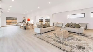 A spacious living room with a large window, a dining area, and a sofa set.