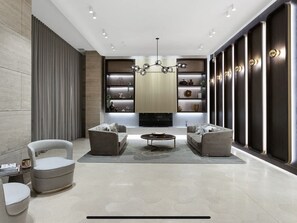 Relax in a comfortable seating area with two sofas and a round coffee table, surrounded by shelving units and a striking chandelier.