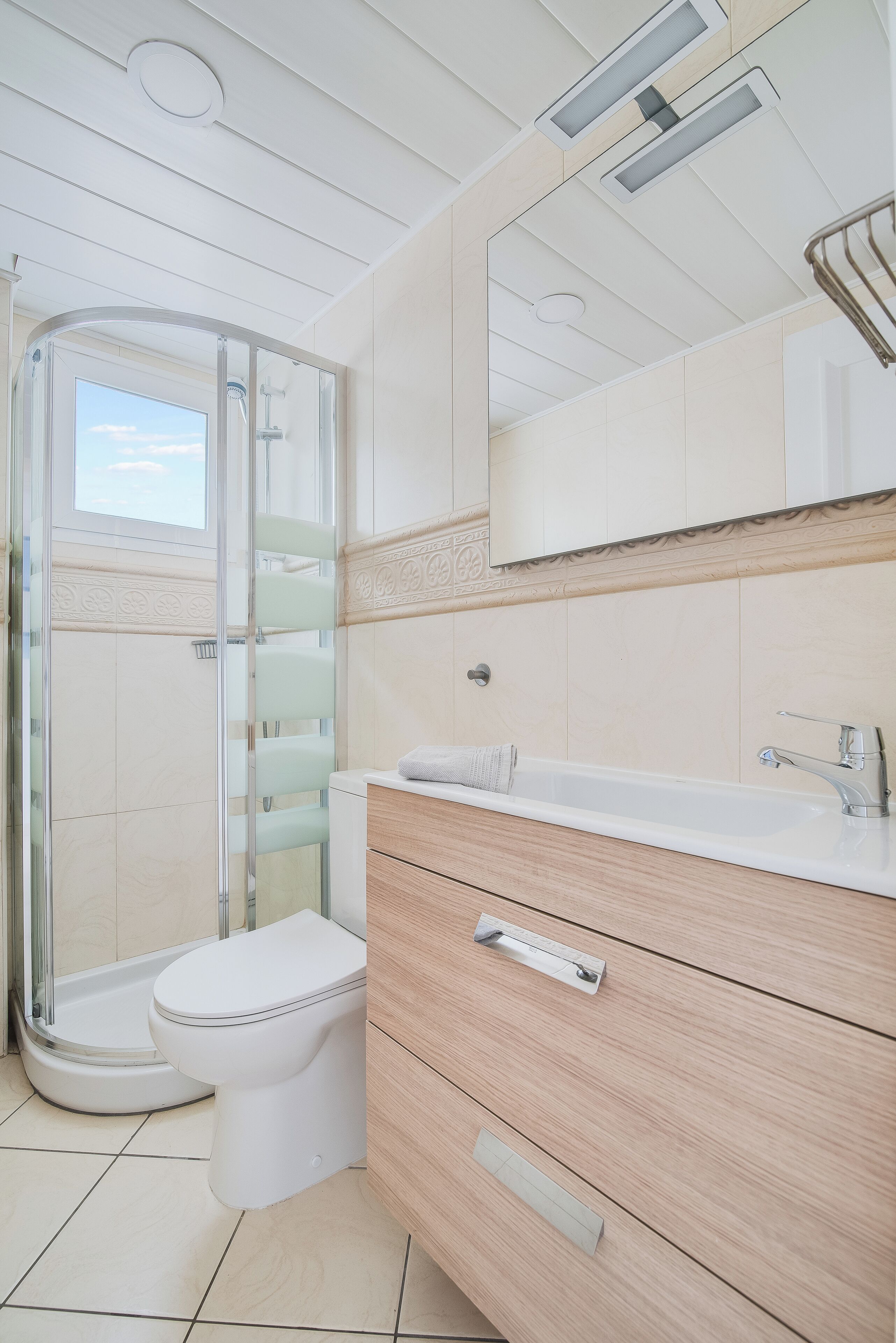 Un baño moderno con cabina de ducha de vidrio, inodoro blanco, tocador con espejo y bañera.