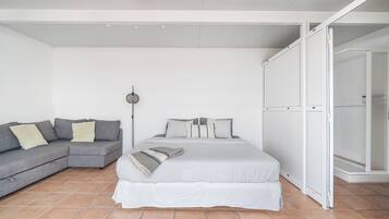 Un dormitorio con cama, sofá gris y vestidor.