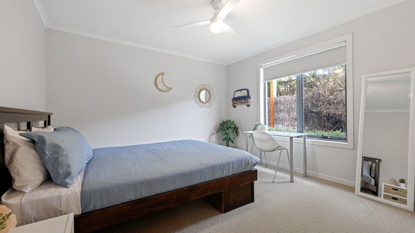 A bedroom with a bed, a desk, and a window.