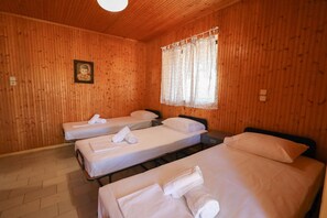 A wooden cabin with three single beds, each with a rolled towel.