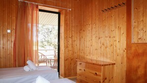 A wooden room with two beds, a wooden dresser, and a door leading to an outdoor area. - Seaside serenity apartment (Ermionida)