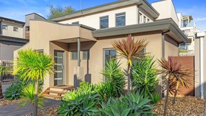 A modern two-story house with a flat roof, large windows, and a well-maintained garden with various plants. - Cowes Central Getaway (Cowes)