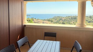 Un balcón con vista al mar, una mesa y dos sillas.