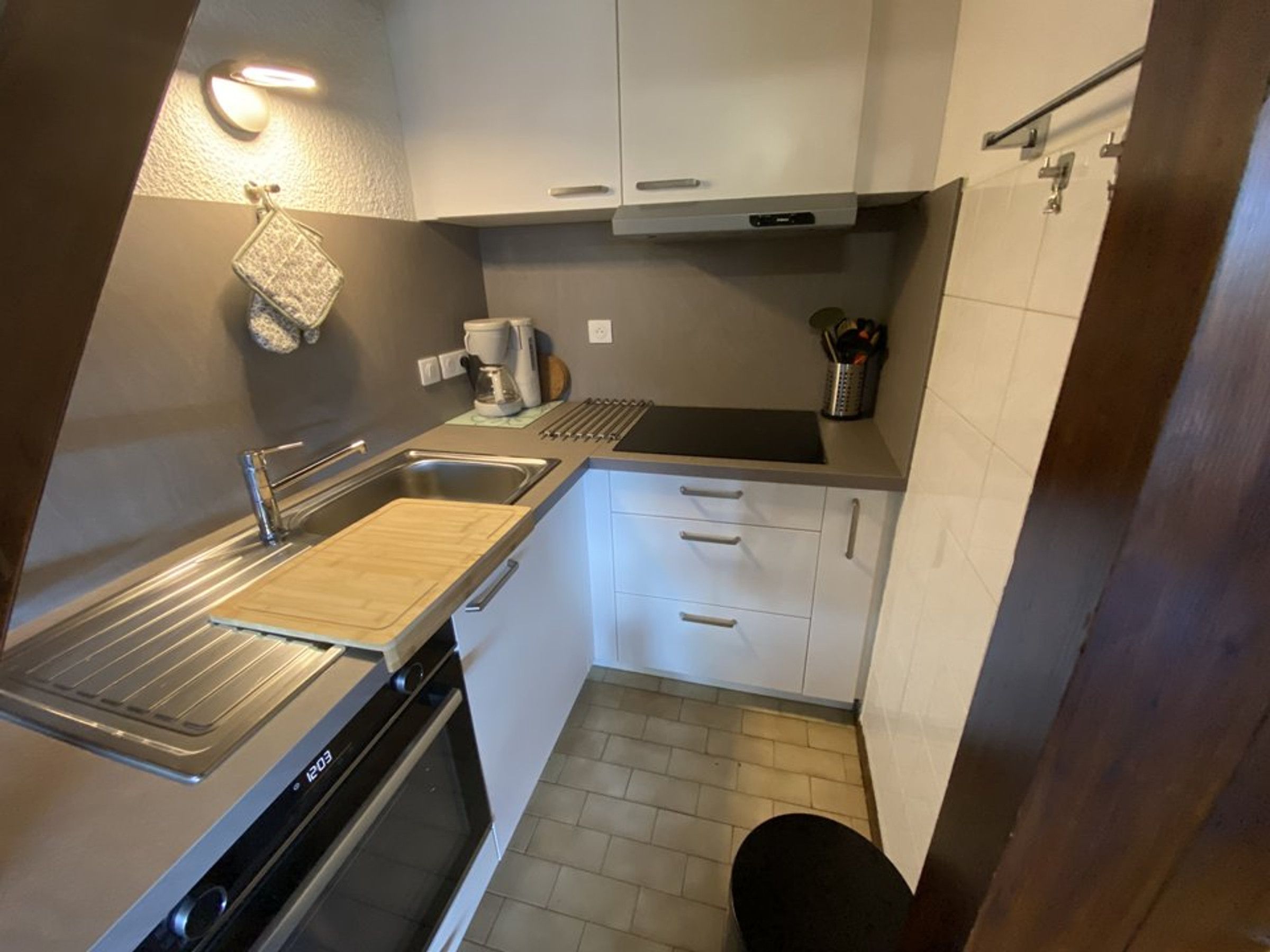 Una cocina funcional con estufa, lavamanos y una pequeña encimera.