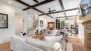 A spacious living area with a high ceiling, wooden beams, and a fireplace.