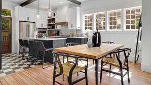 A modern kitchen with white cabinets, a central island, and a dining area with a wooden table and chairs.