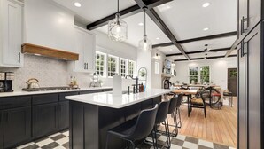 A modern kitchen with a large island, black bar stools, and a checkered floor.