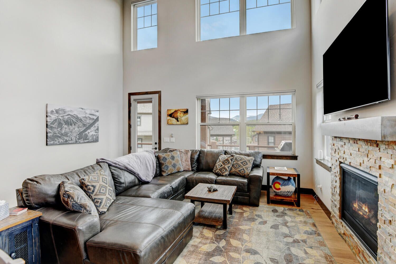A spacious living room with a sectional sofa, a fireplace, and large windows.