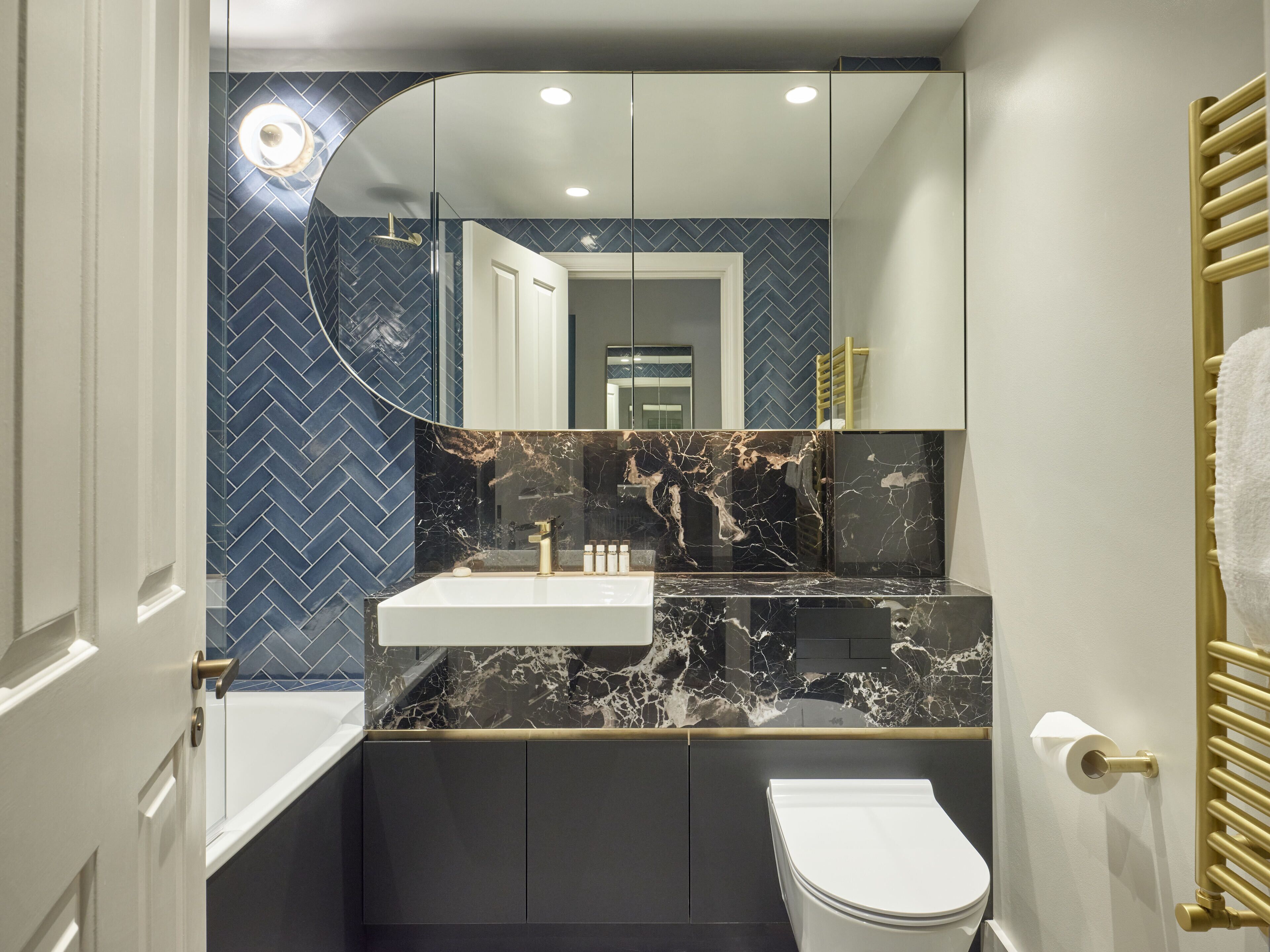 A modern bathroom with a white sink, marble countertop, and a toilet.