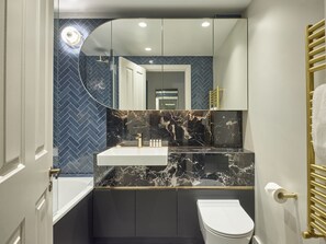 A modern bathroom with a white sink, marble countertop, and a toilet.