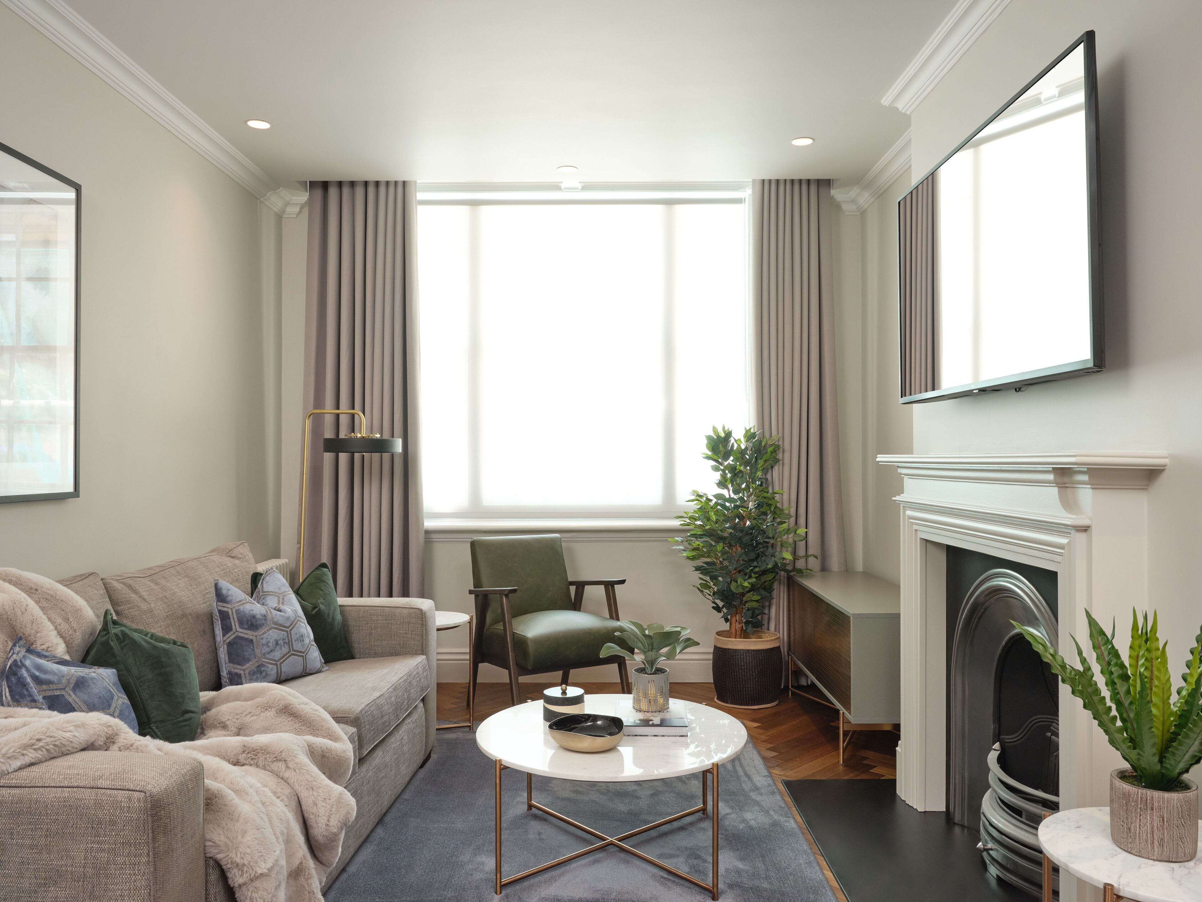 A modern living room with a sofa, a coffee table, a fireplace, and a large window.