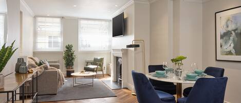 Een moderne woonkamer met een bank, salontafel en een eetgedeelte met stoelen en een tafel gedekt voor een maaltijd.
