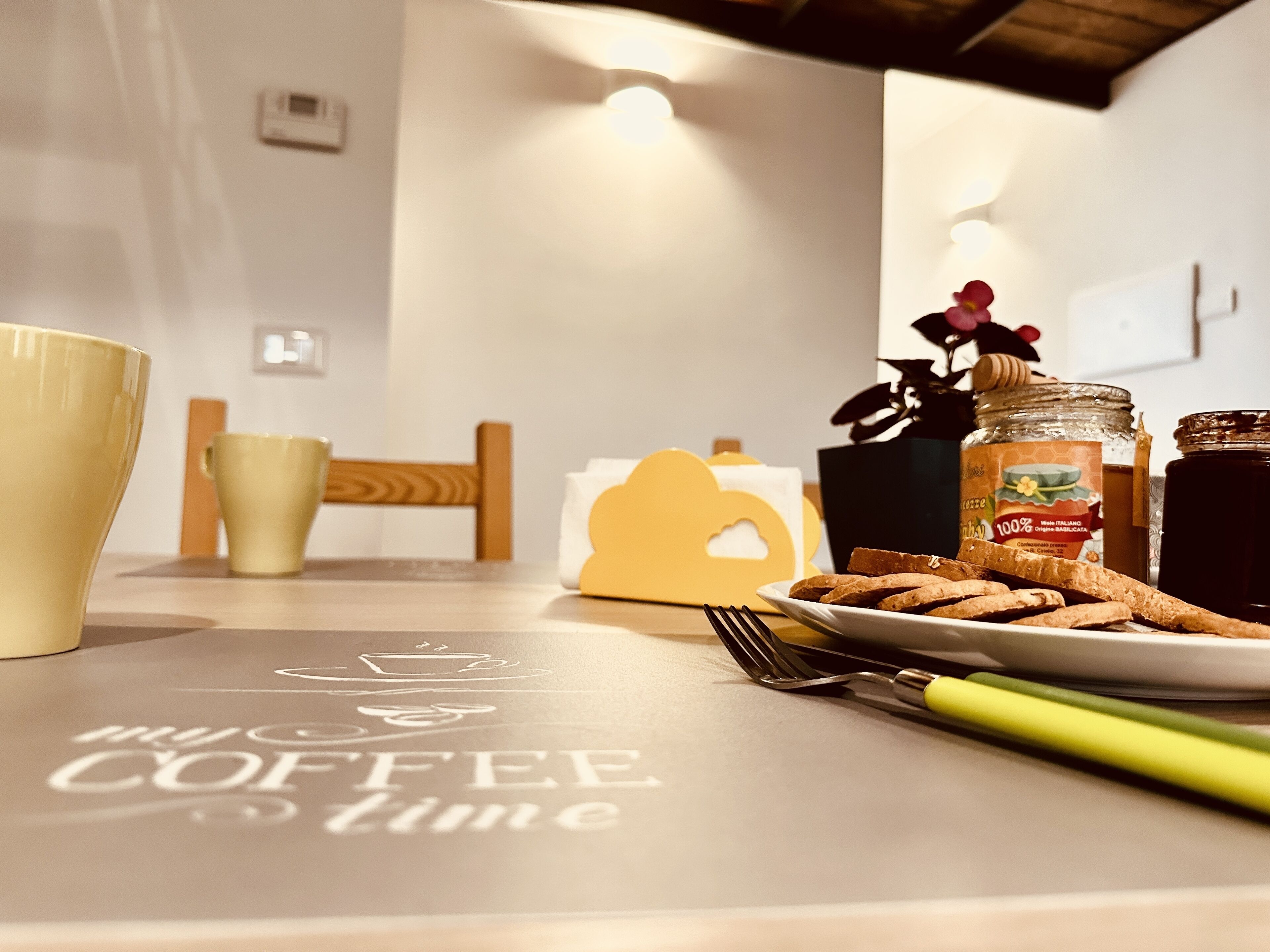 Ein Tisch mit einer Platte Biscotti, einem Honigglas und einer Kaffeetasse.